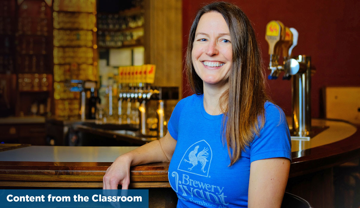 Woman standing in front of bar with blue Brewery Vivant tshirt