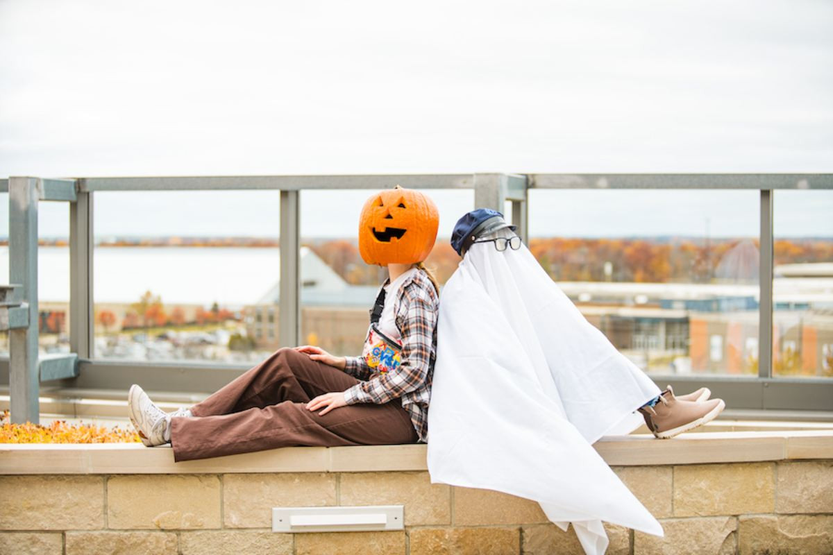 a ghost and another student with a pumpkin on their head for Halloween