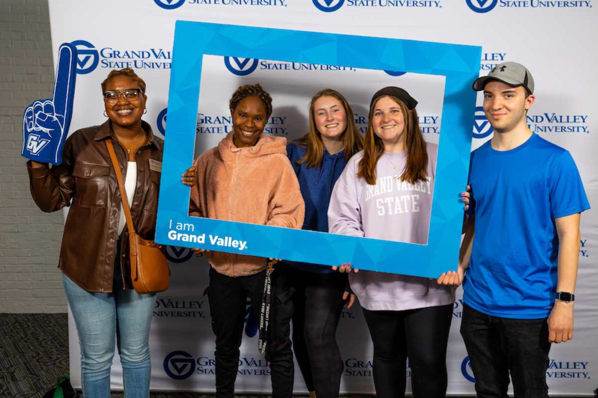 A group of students posing for a picture after being nominated and holding a frame that says I am Grand Valley