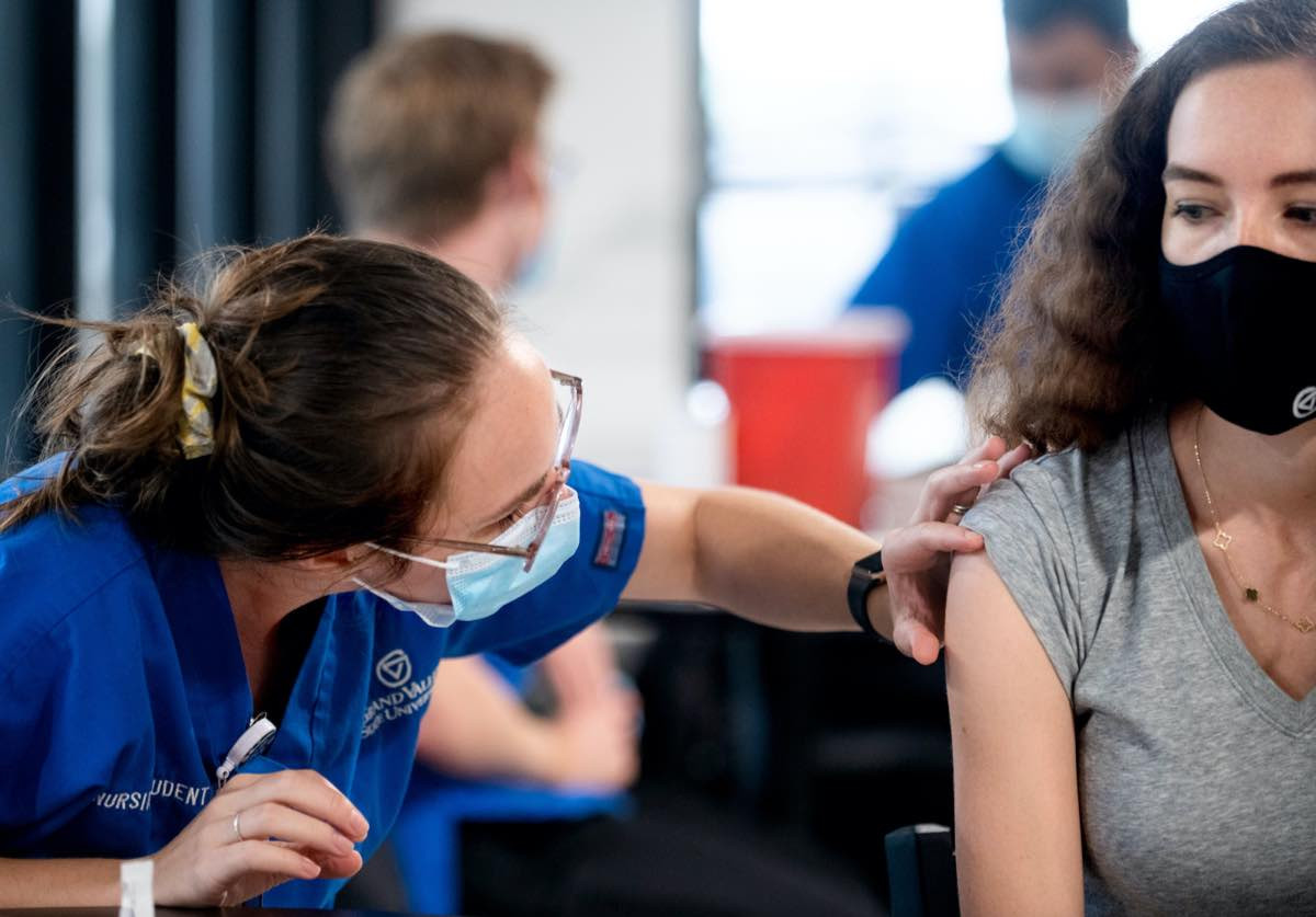 Medical professional examines student's arm prior to administering vaccine