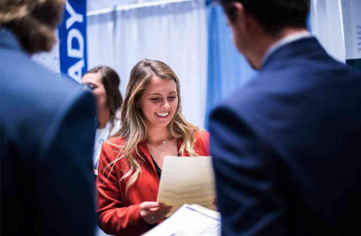 A student smiling at their resume at a career fair