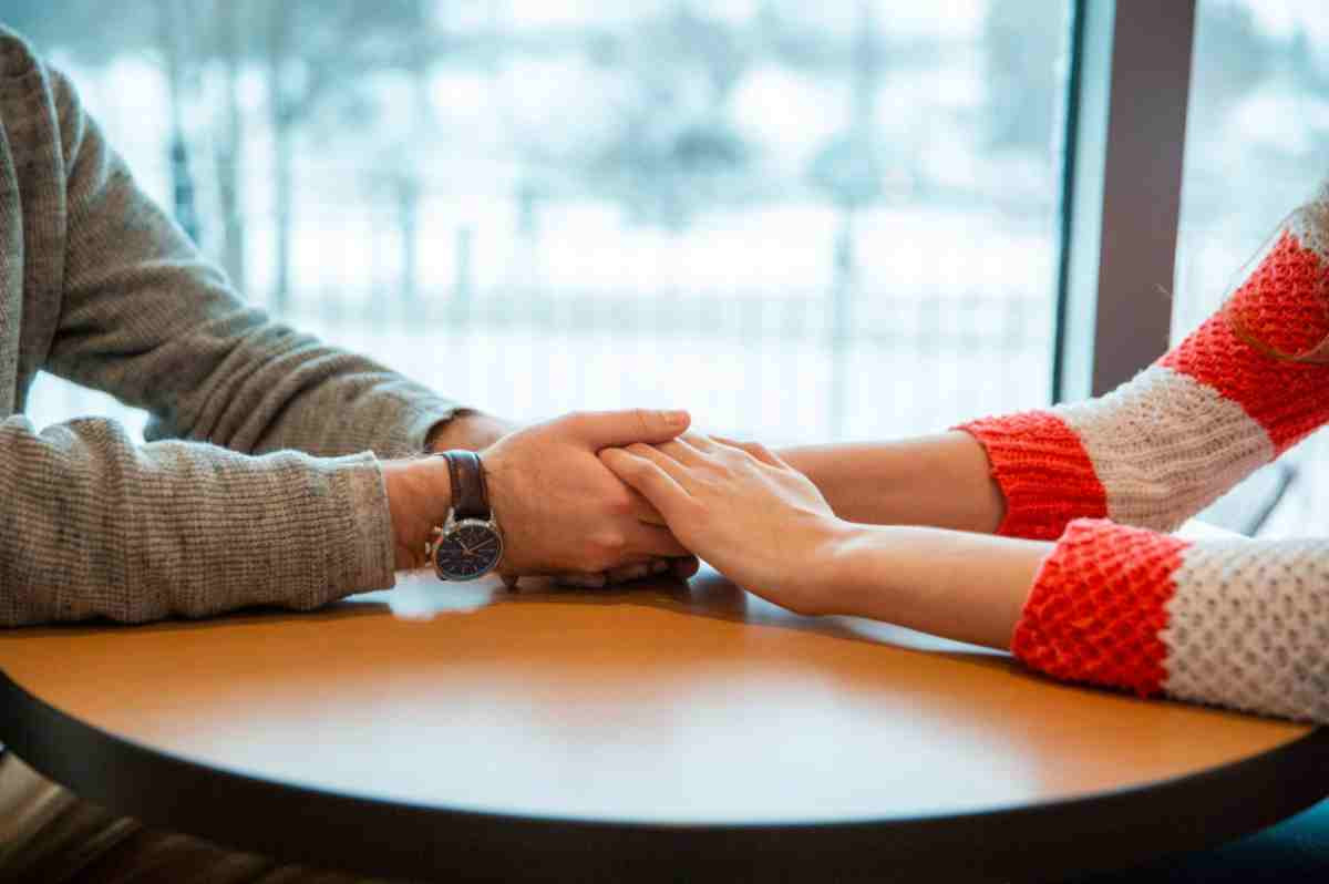 Two pairs of hands holding on a table