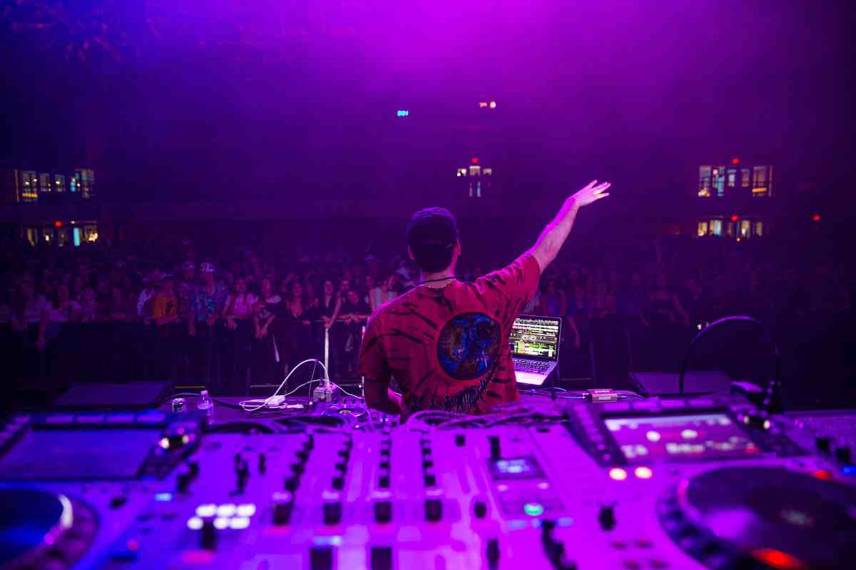 DJ with his hand up with the crowd in the background