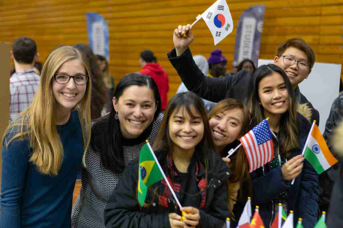 Students smiling for a group picture holding flags from different countries