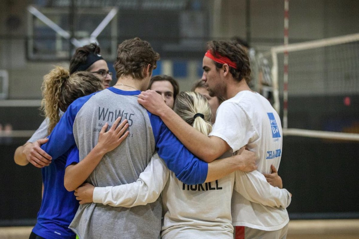 people in a huddle on a volleyball court