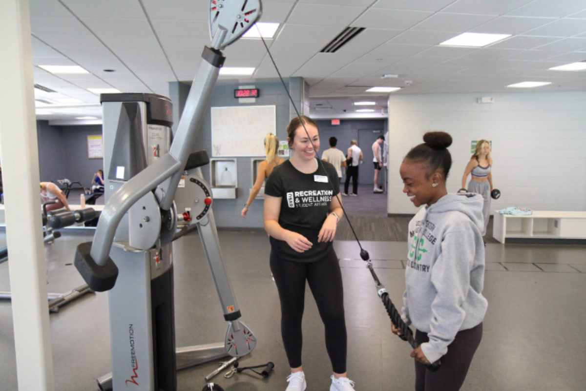 A fitness trainer working with a student in the Rec Center