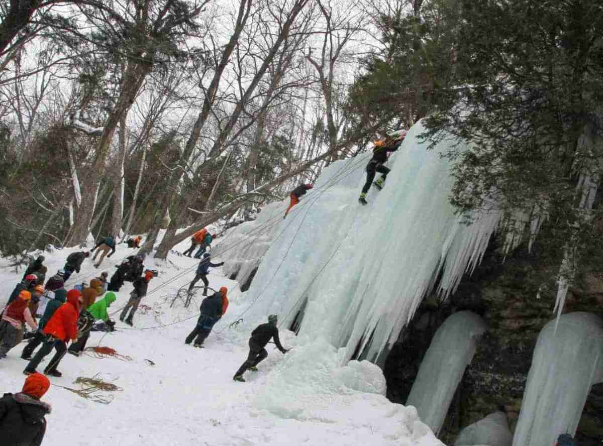 People climbing Pictured Rocks with ice covering it