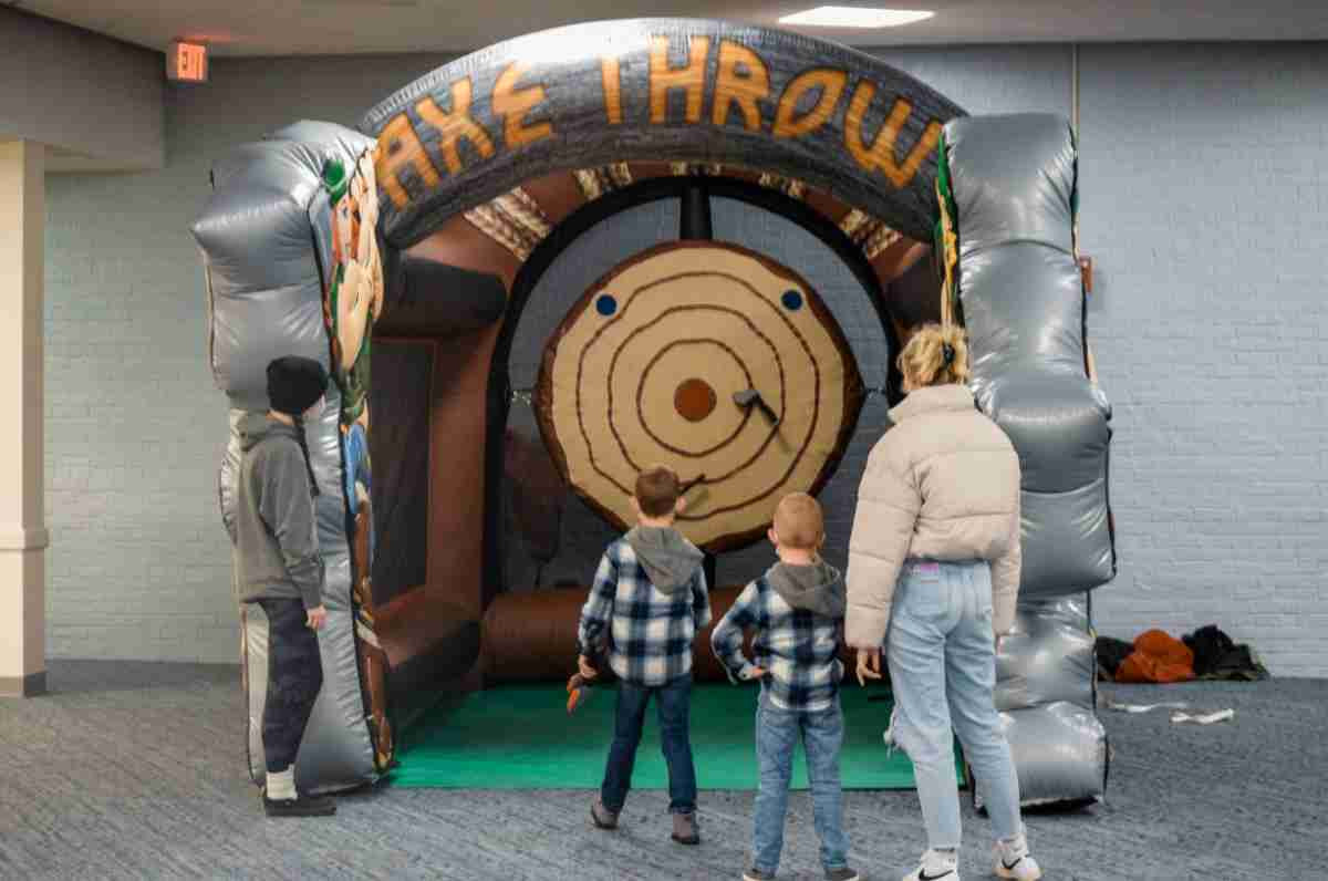 A student standing with their sibling while paying with the inflatable axe throwing game