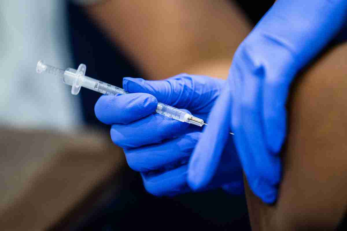 Doctors hands in gloves giving someone a flu shot.