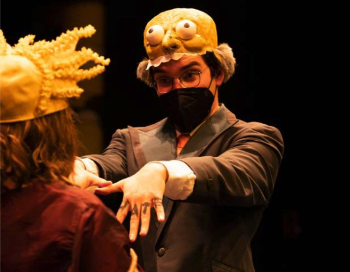 Theater at gvsu performance. A student with a hat on holding out their arms