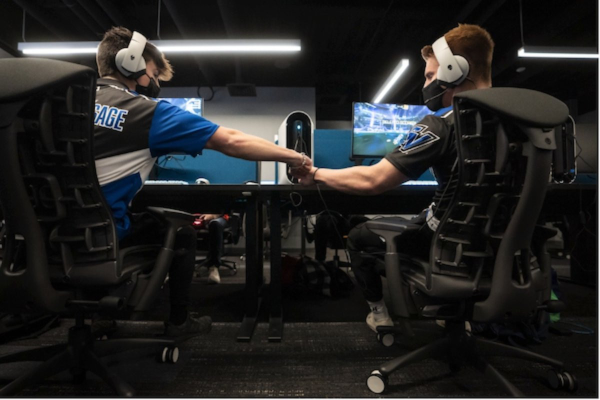 two guys shaking hands in front of computers