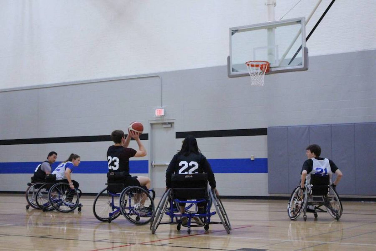 Five people wearing jerseys as they participate in Wheelchair basketball