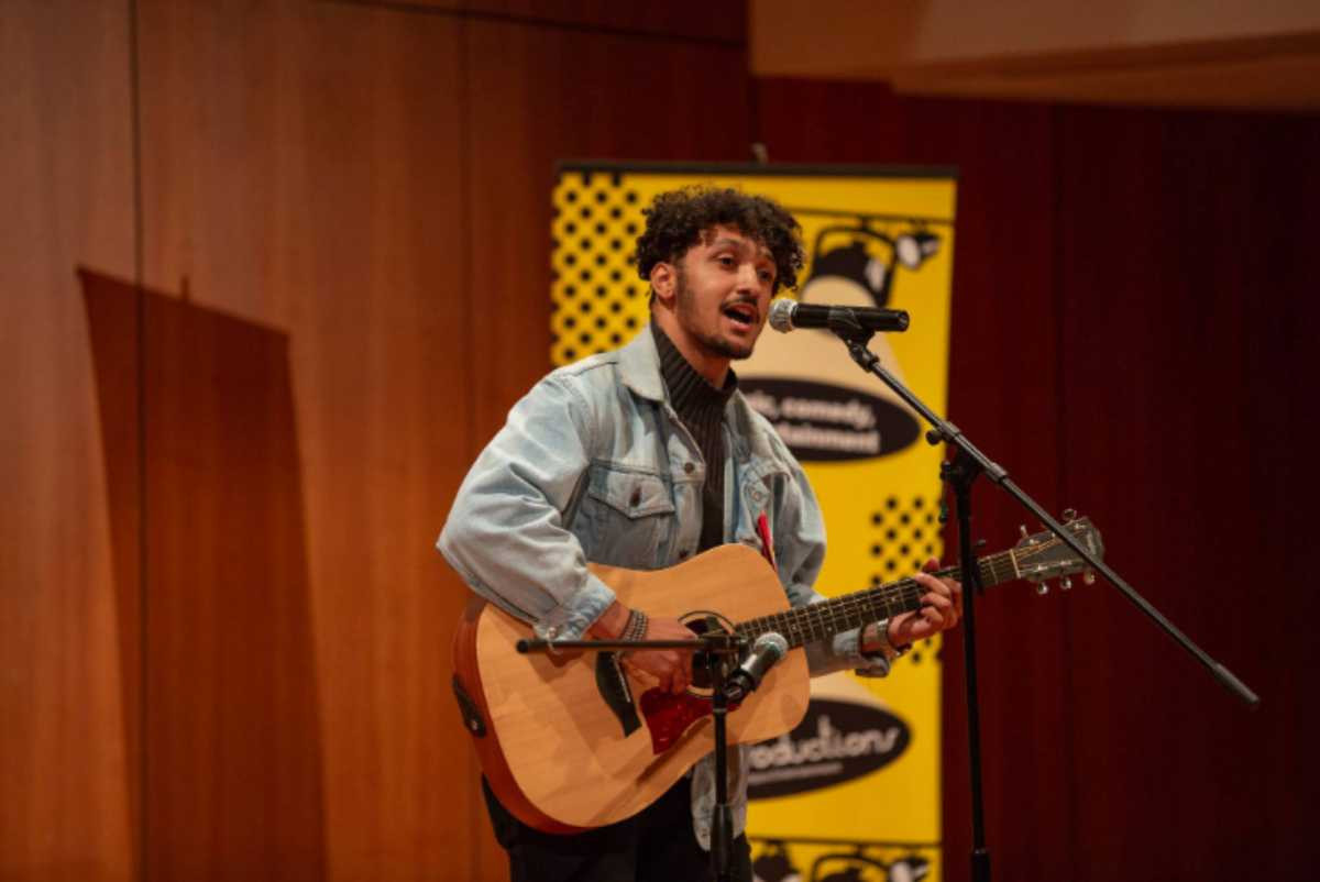 A student performer singing and playing guitar at GV's got talent