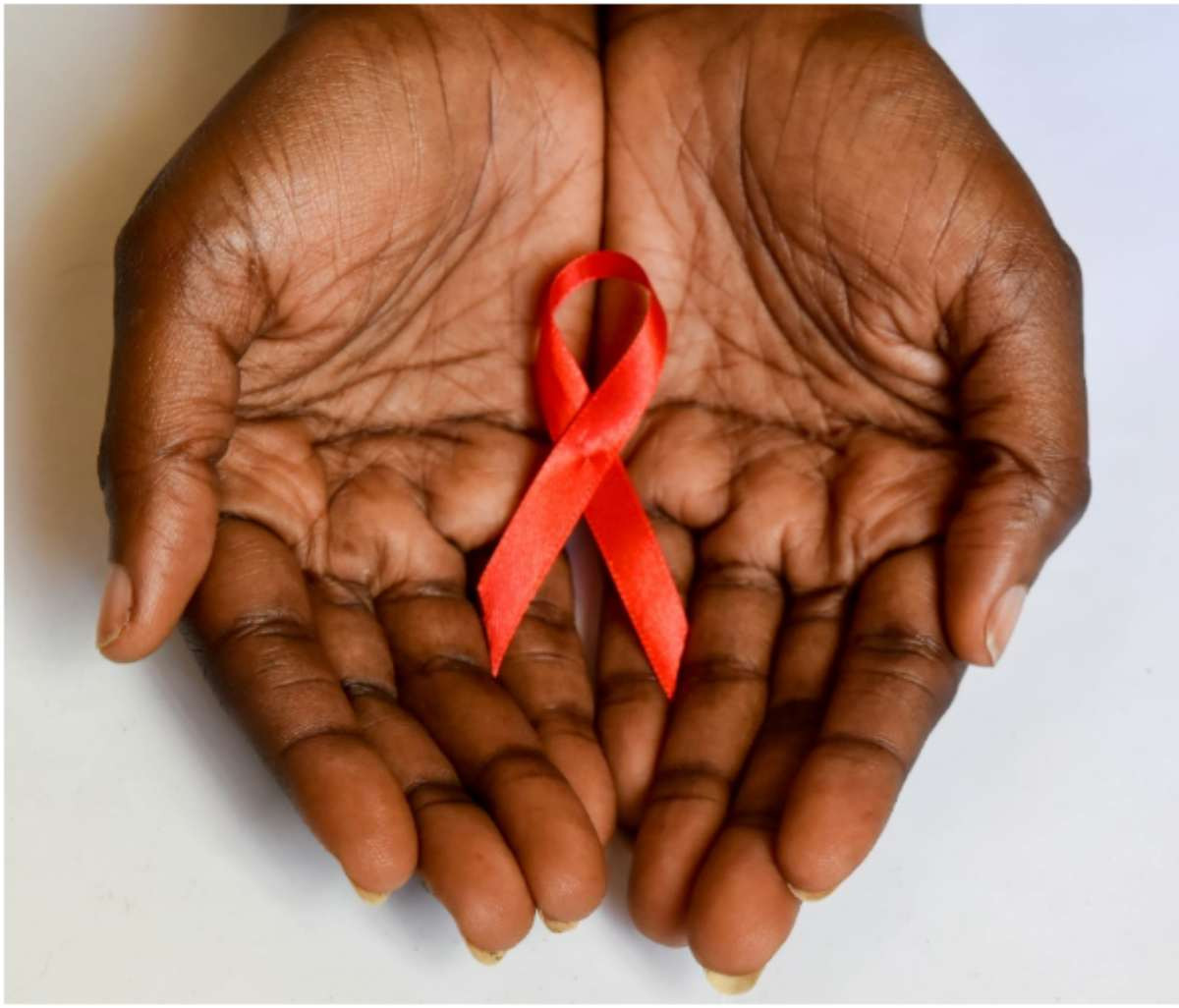 Hands cupped together holding a red awareness ribbon