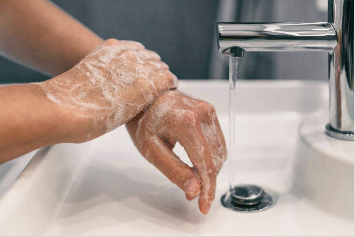 A person washing their hands in the sink with sudsy soap on their hands