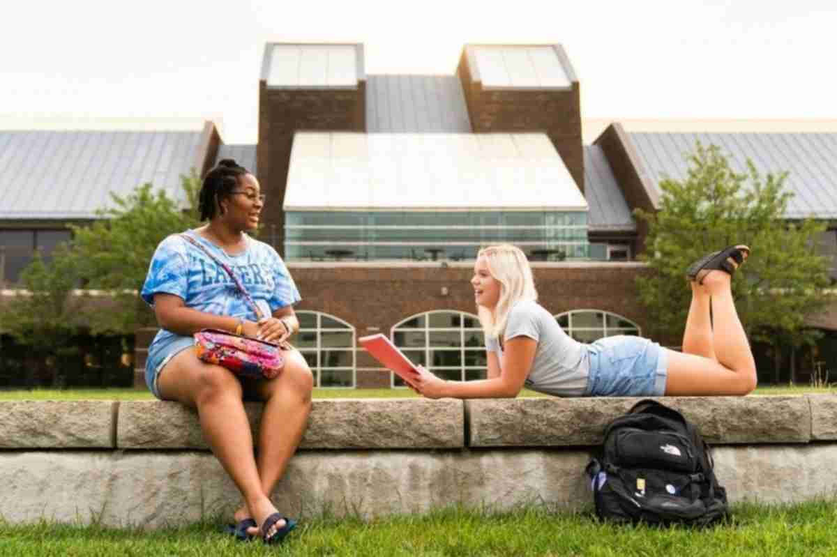 two students chatting on the Kirkhof Lawn in front of the Zumberg pond