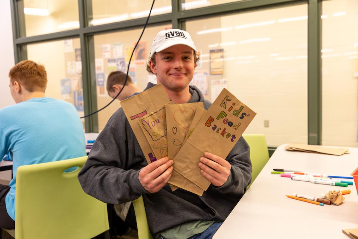 A student decorating bags as he volunteers during Drop-In Services.