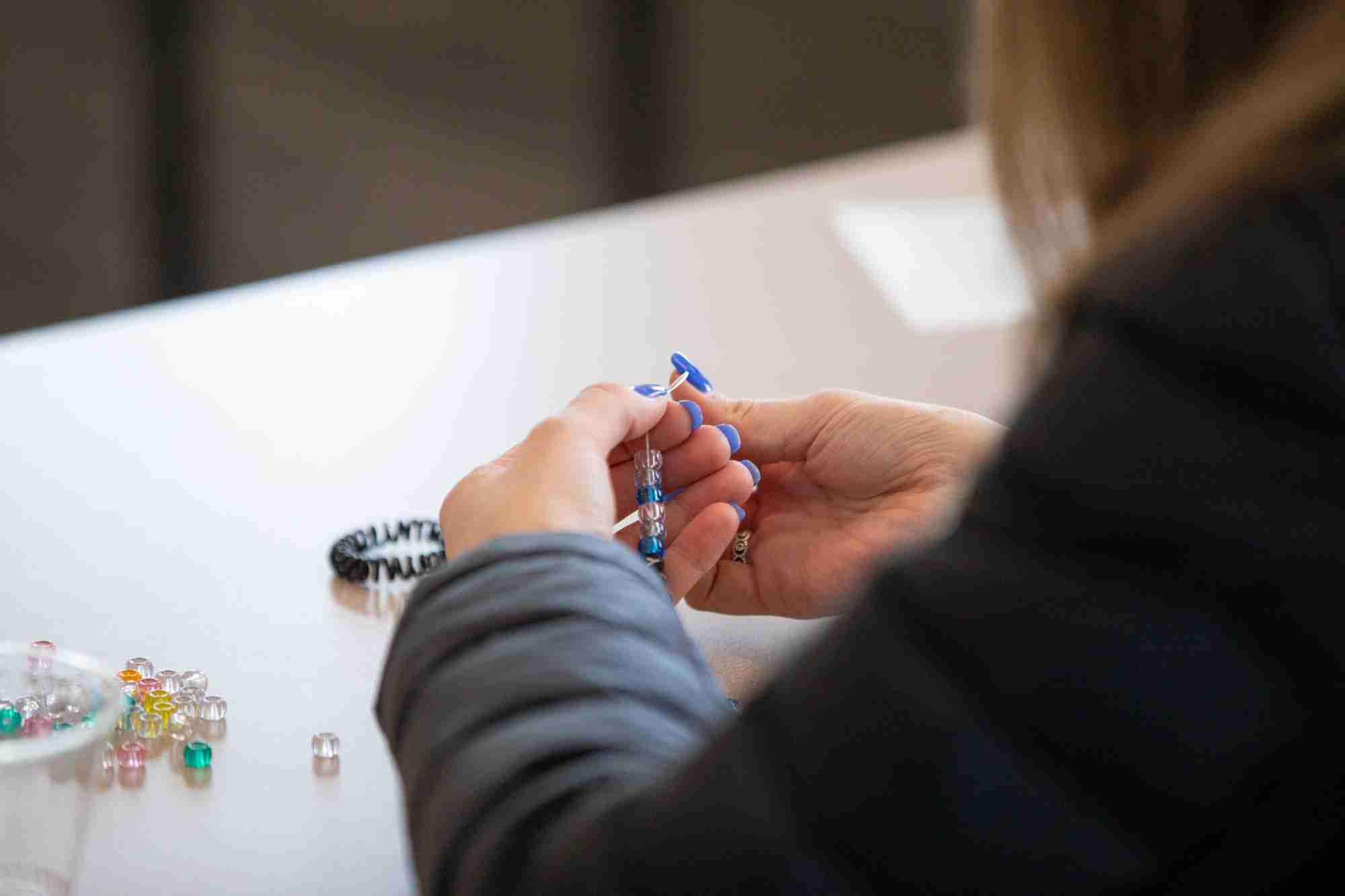 Student making bracelets for Drop-in Days of Service