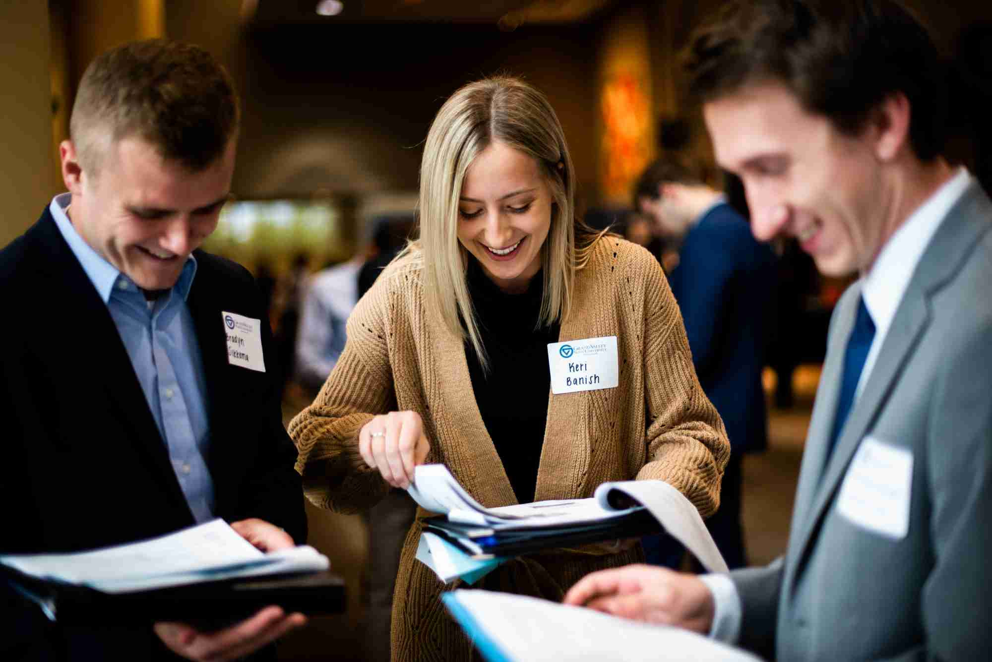 Three students smiling at their resumes