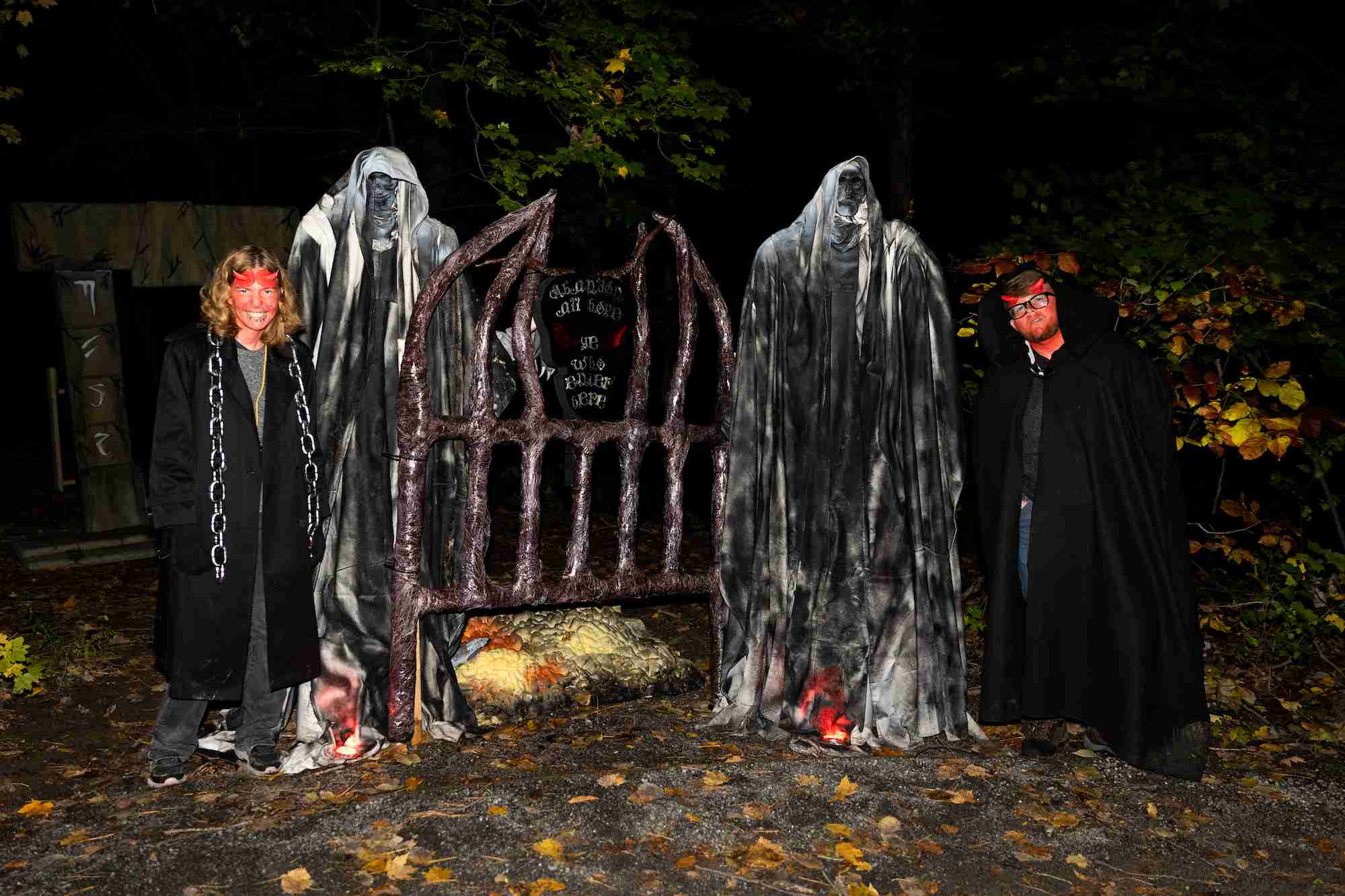 Two people dressed as devils by a gate at the haunted arboretum