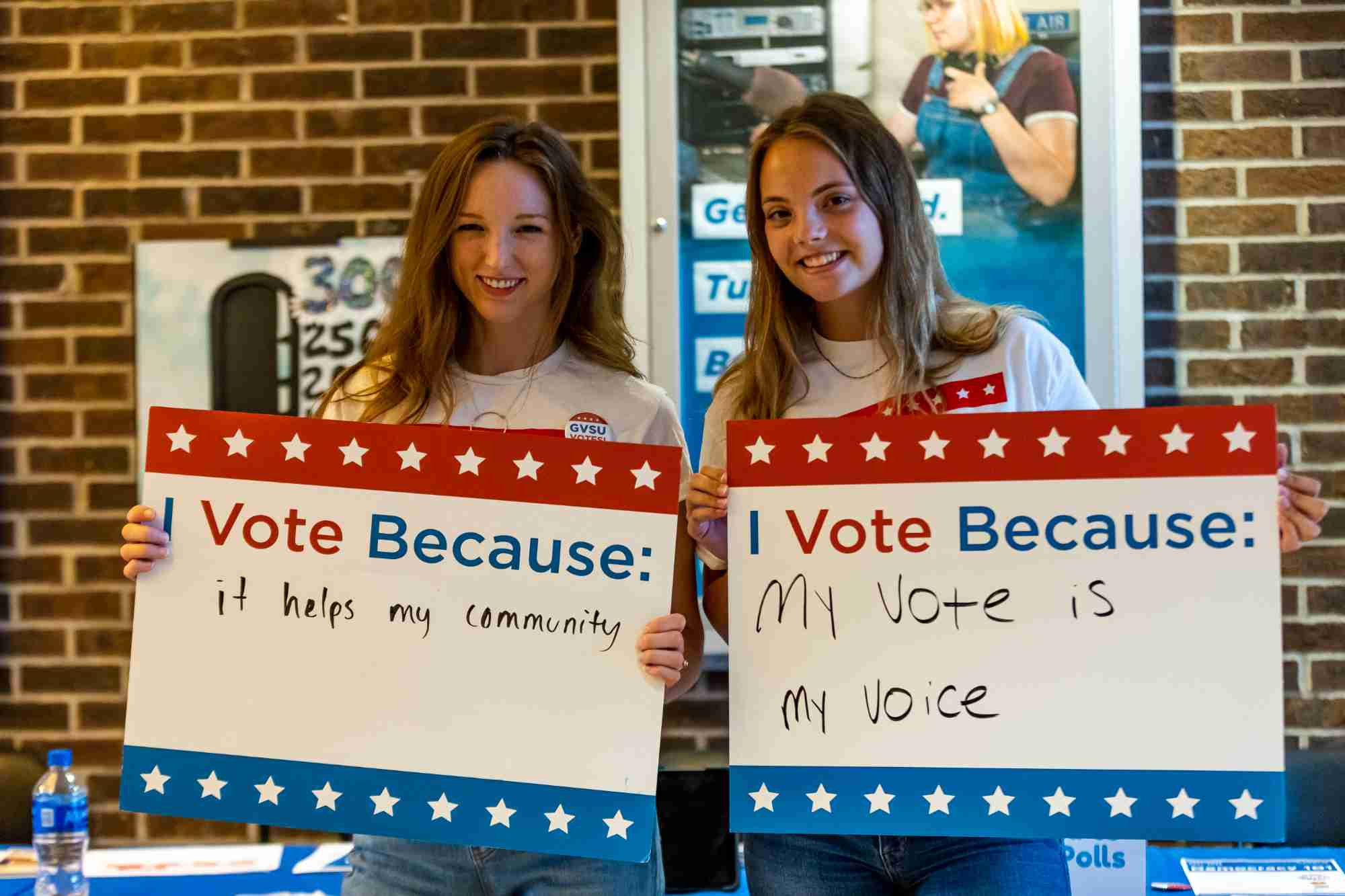 Two students holding up I vote because signs