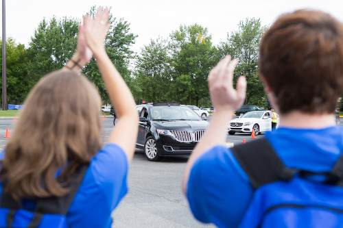 two students cheering as cars are parking