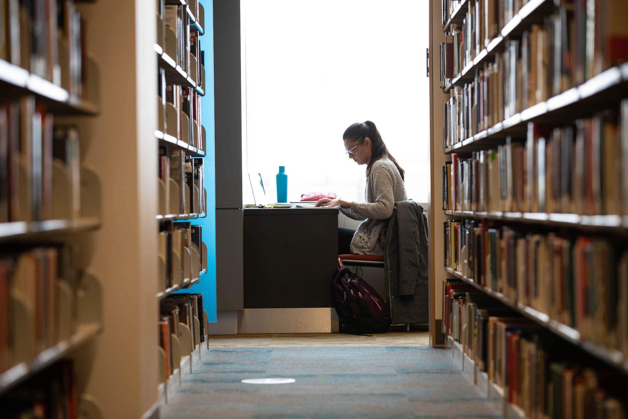 a student sitting behind rows of books studying