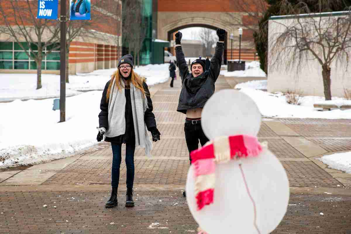 two students celebrating after hitting the snowman with a snowball