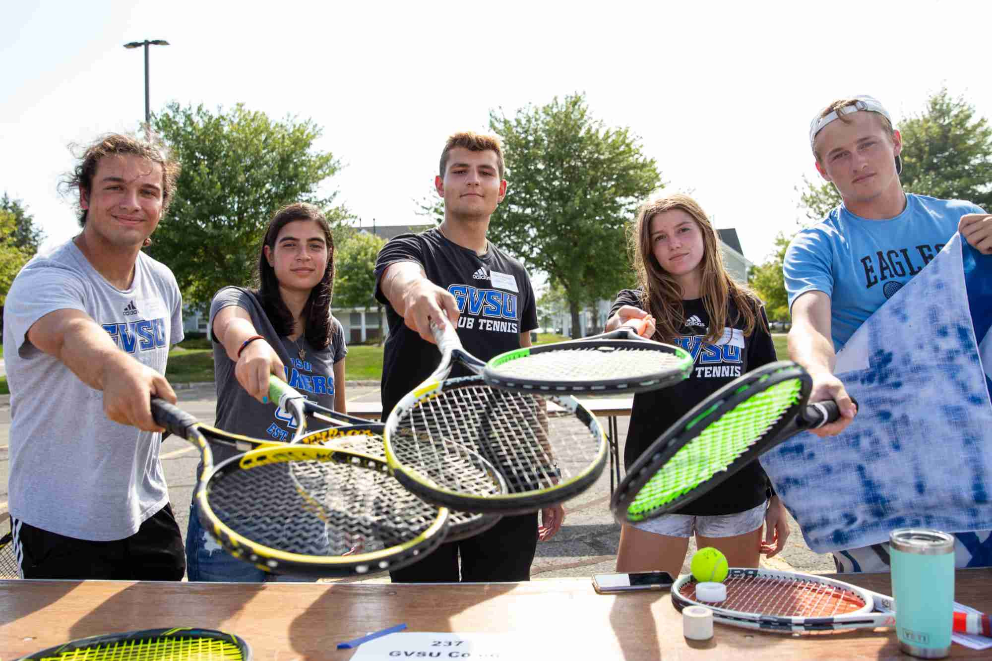 4 students on the tennis team holding their rackets together