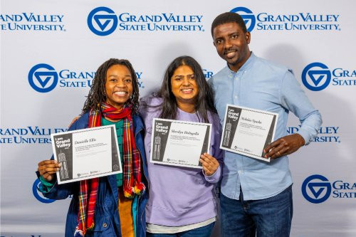 Three students holding up their I Am Grand Valley awards