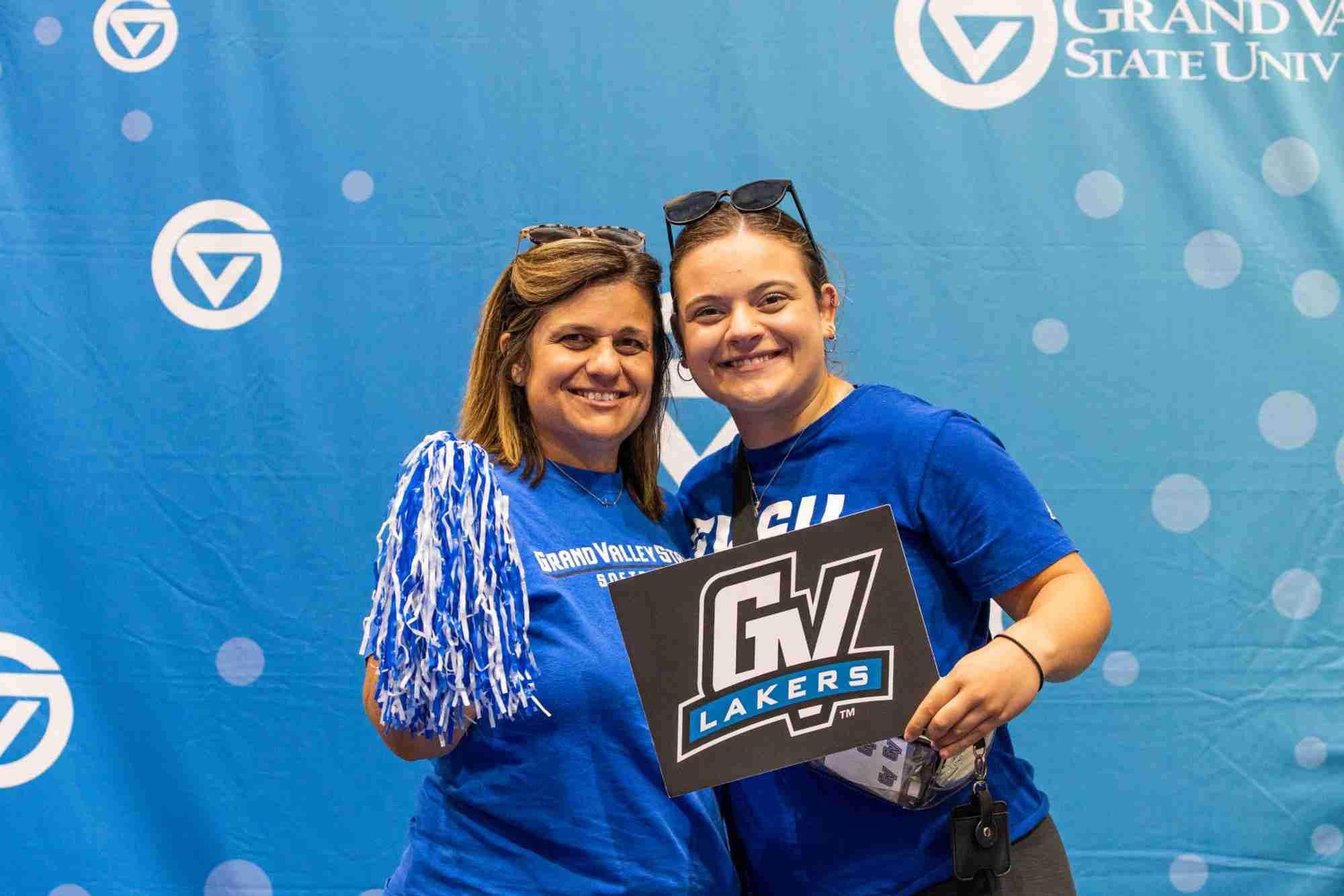 family weekend photo booth: Mom and student with pom poms