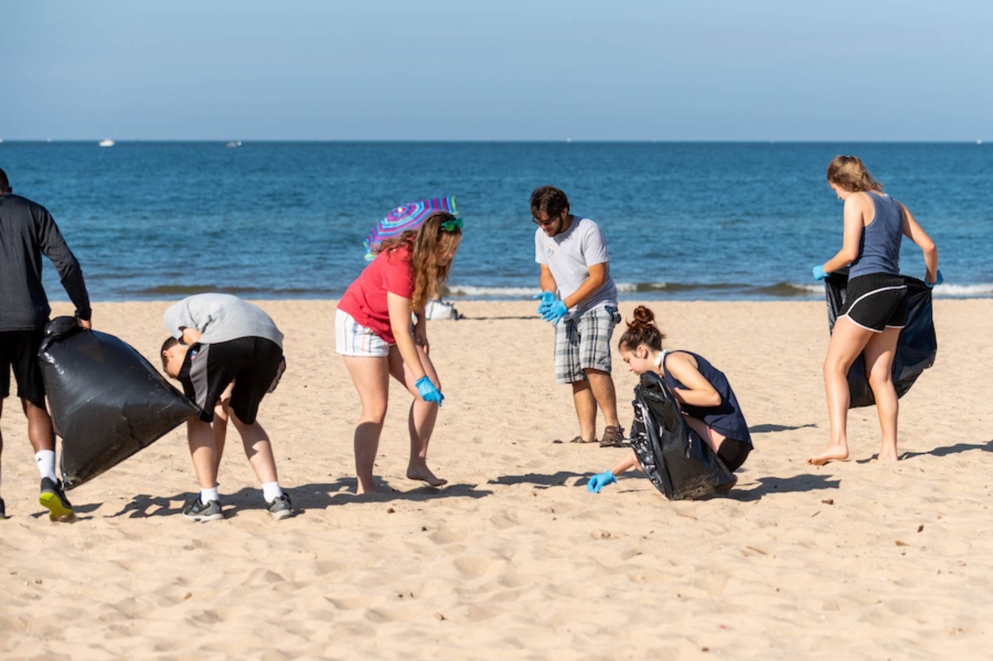 people picking up garbage on a beach