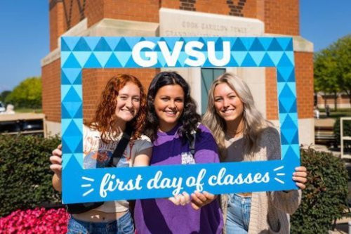 three girls holding a frame that reads gvsu first day of classes