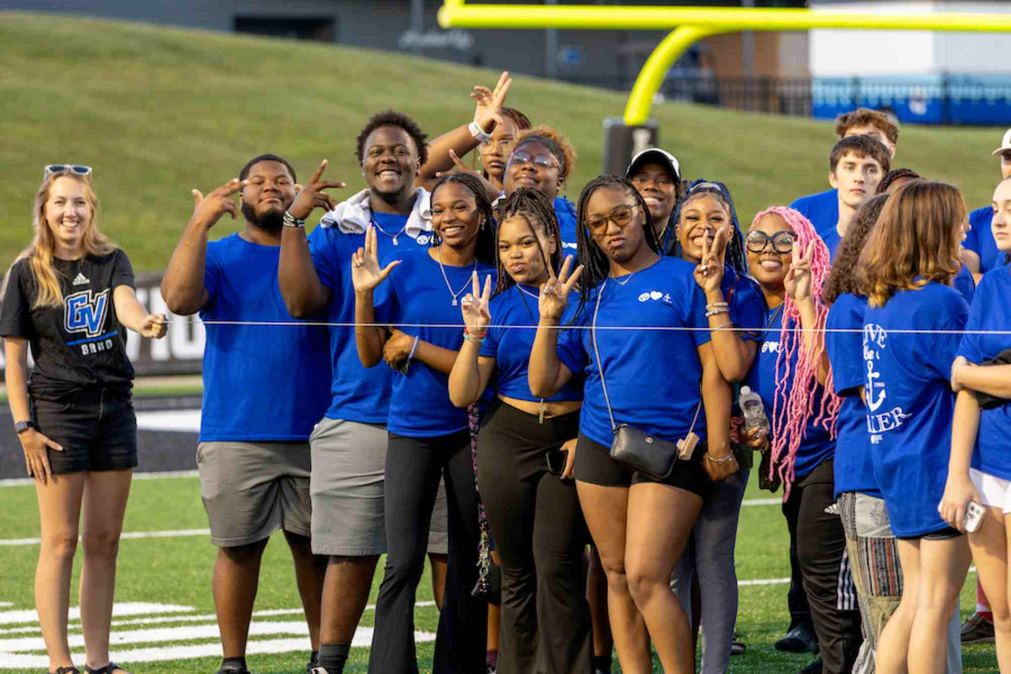 Students doing the Anchor Up Hand Symbol during Convocation