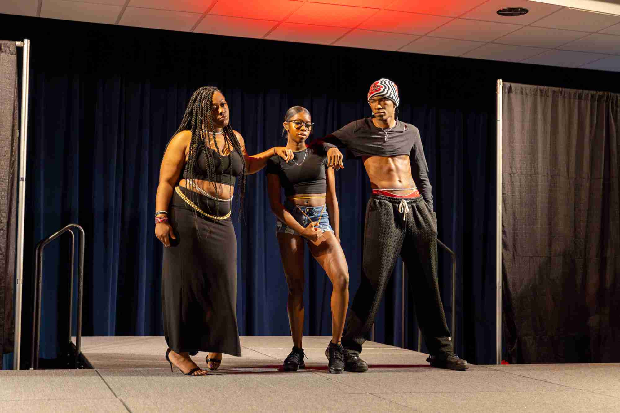 Three Model Entertainment students dressed in black posing onstage
