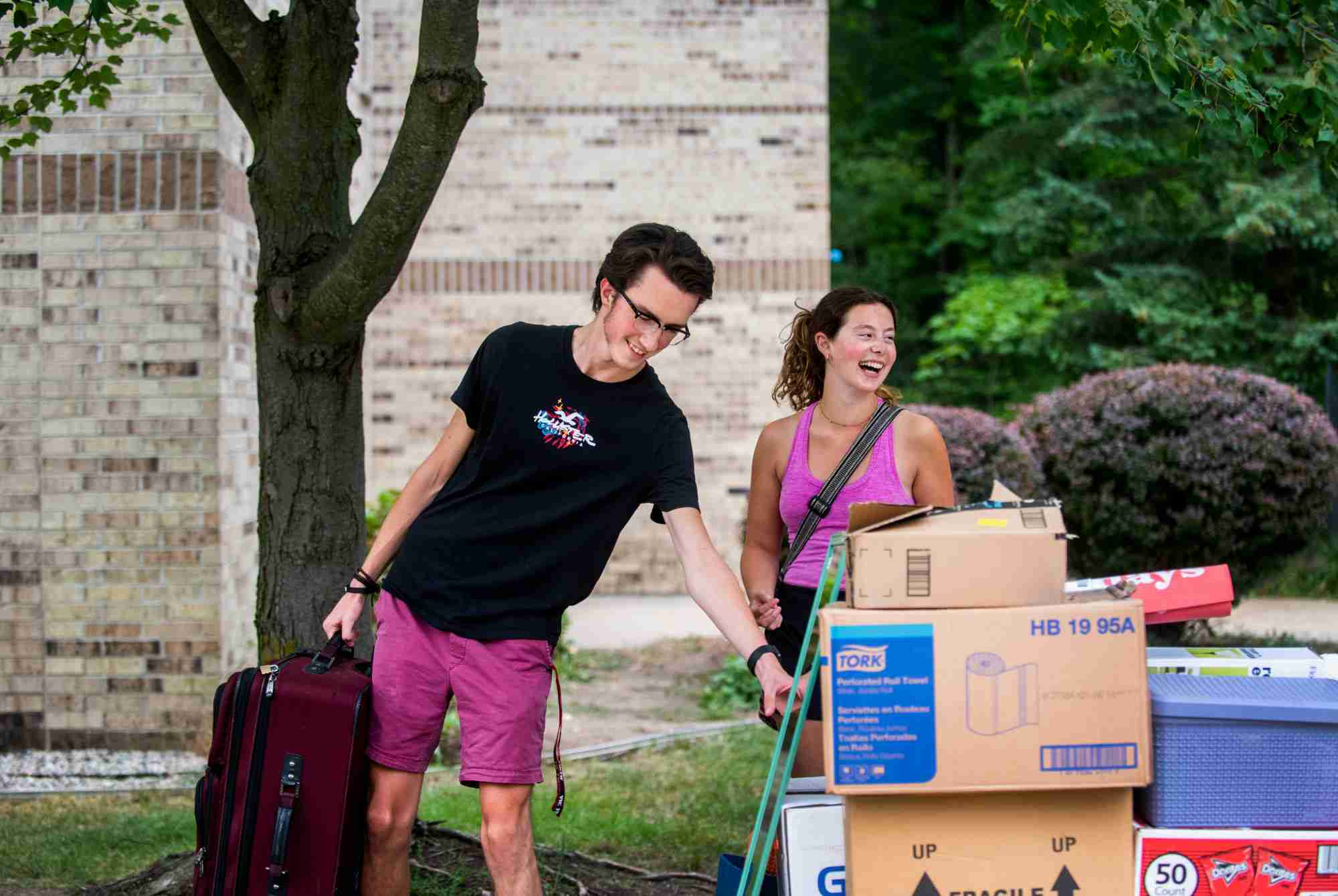 Two people carrying boxes and suitcase