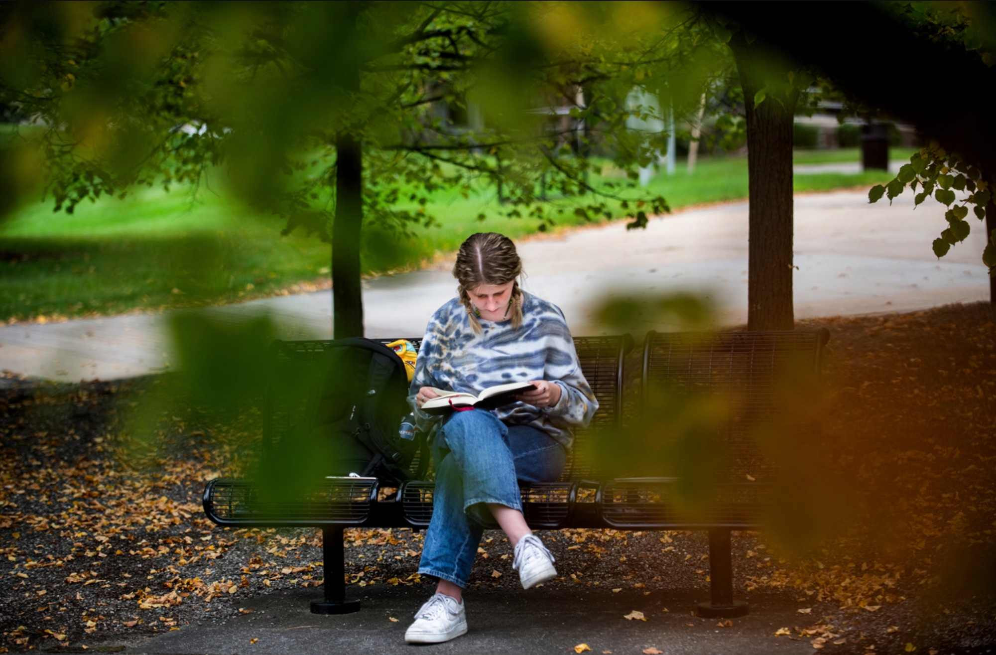 Student sitting on a bench outside reading