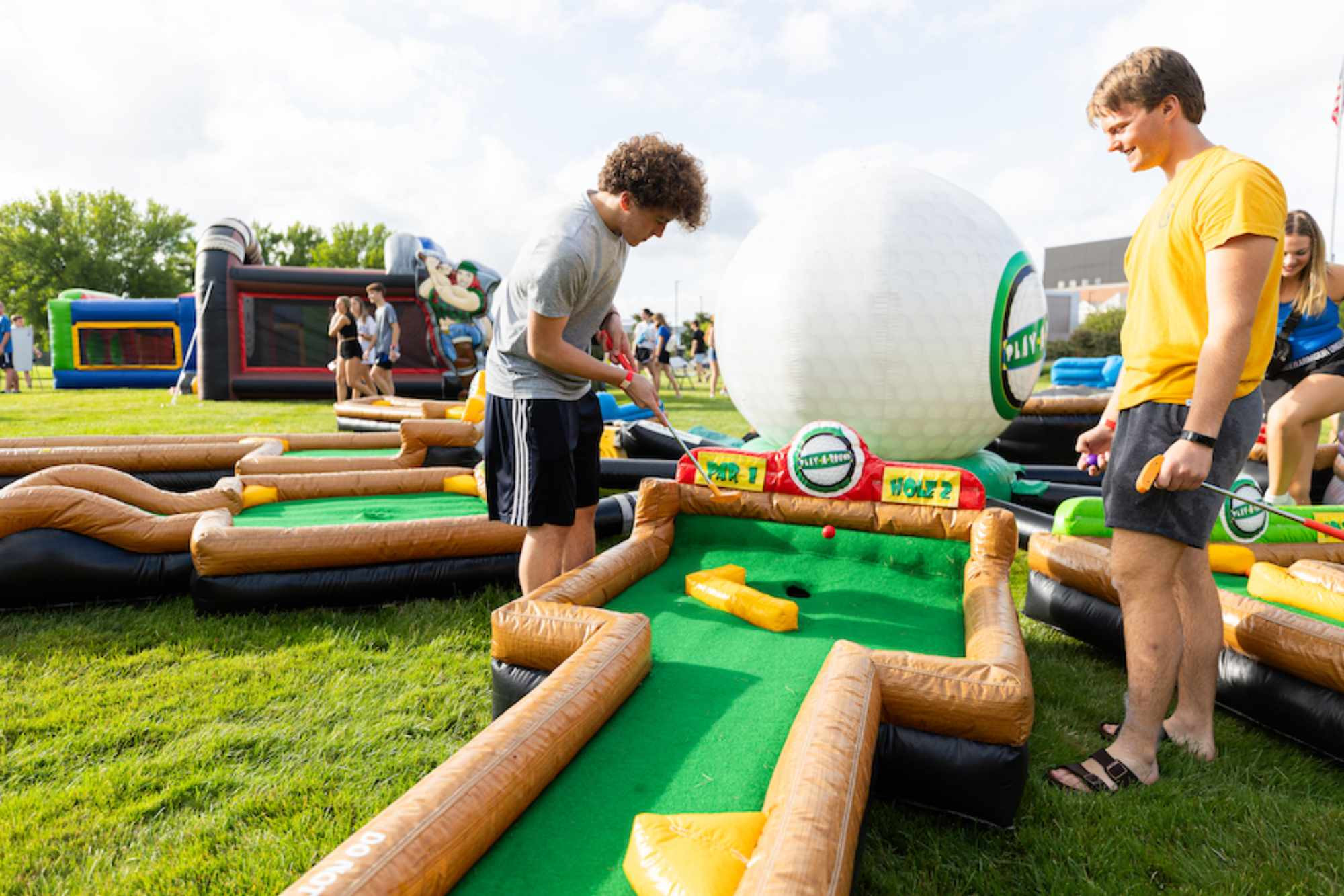 Two friends playing golf at an event with their organization