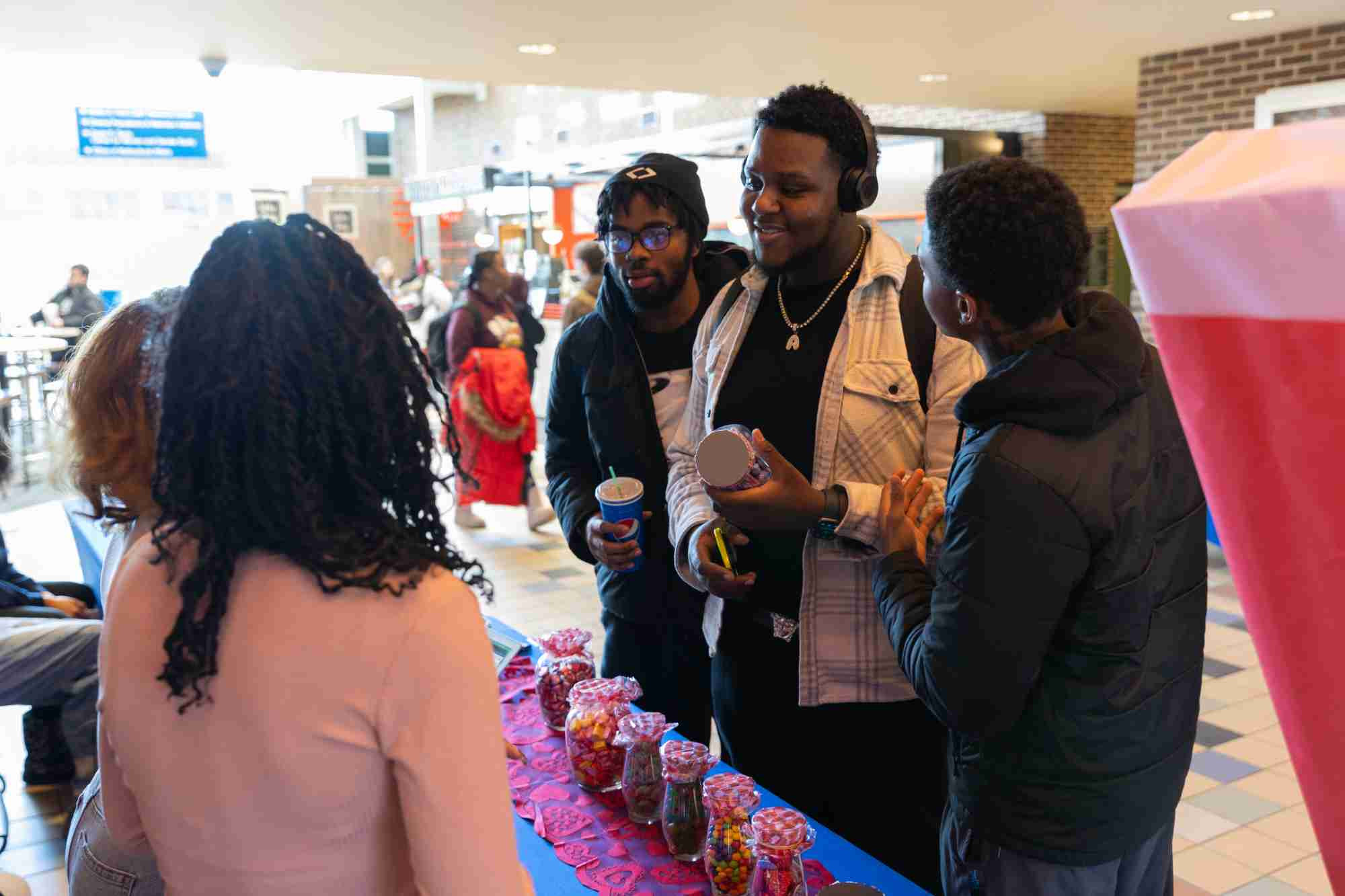 Three students talking to two students tabling at the Black Student Union Love Carnival