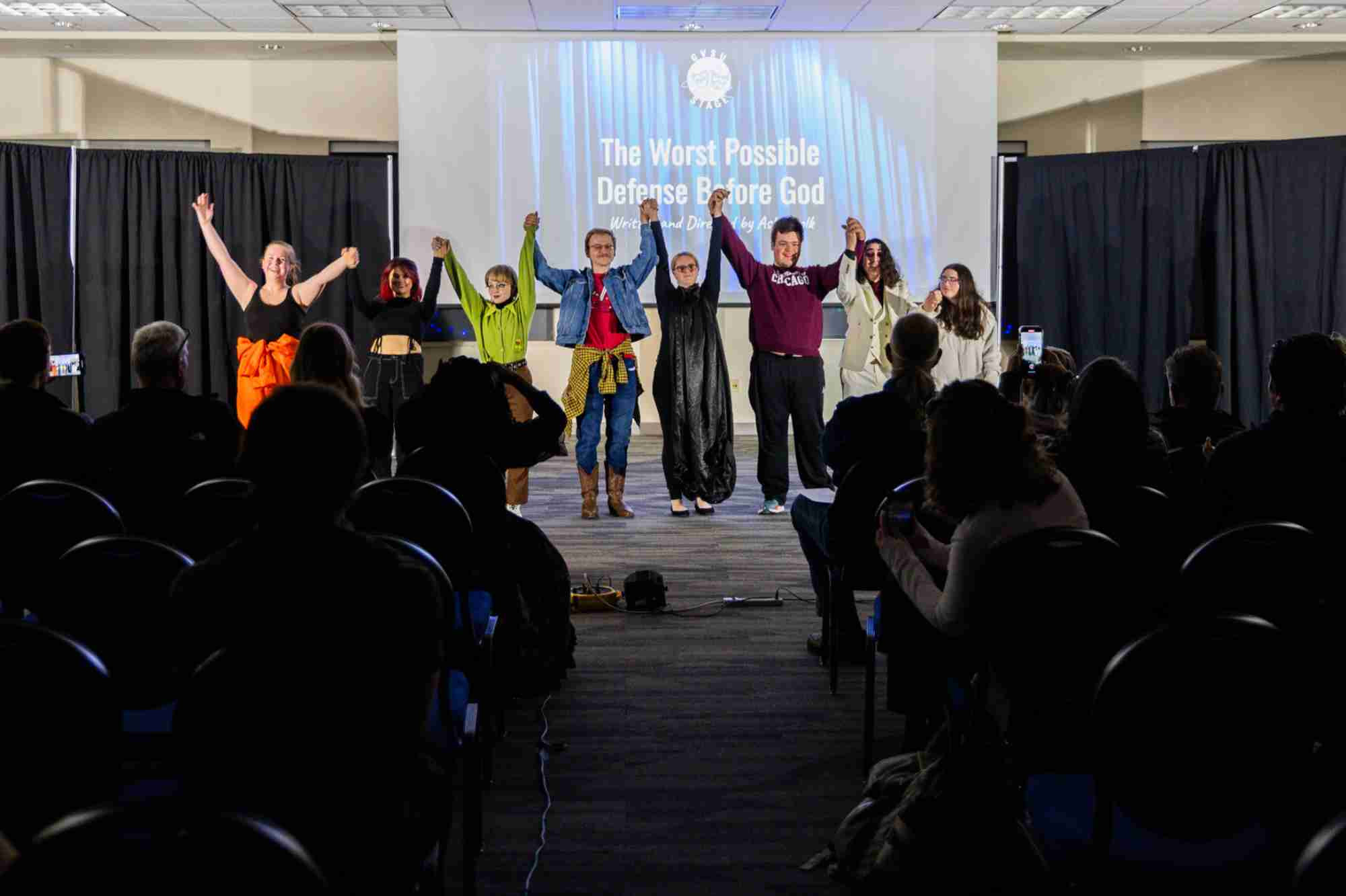 Students hold hands raised in the air right before taking a bow