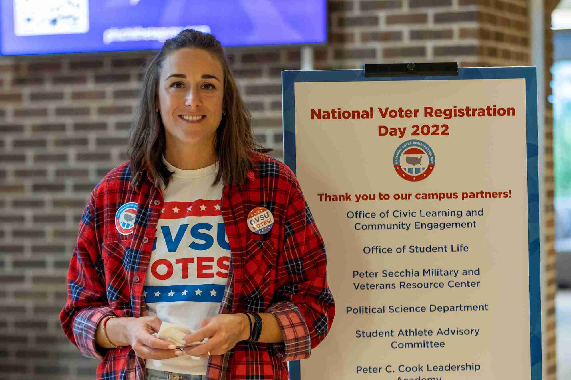 Someone standing in front of national registration day sign smiling