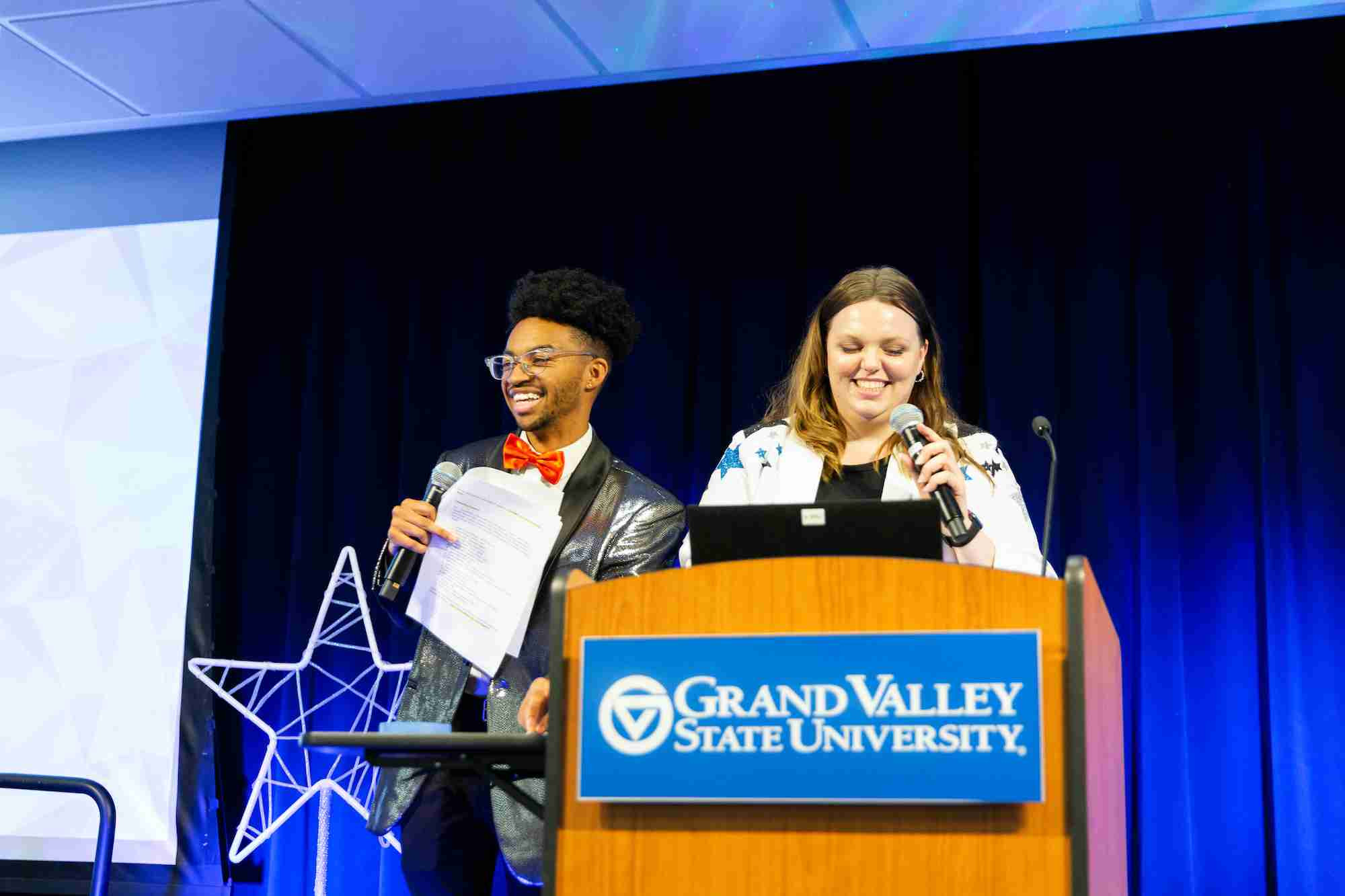 Two facilitators at I Am Grand Valley smiling behind the podium 