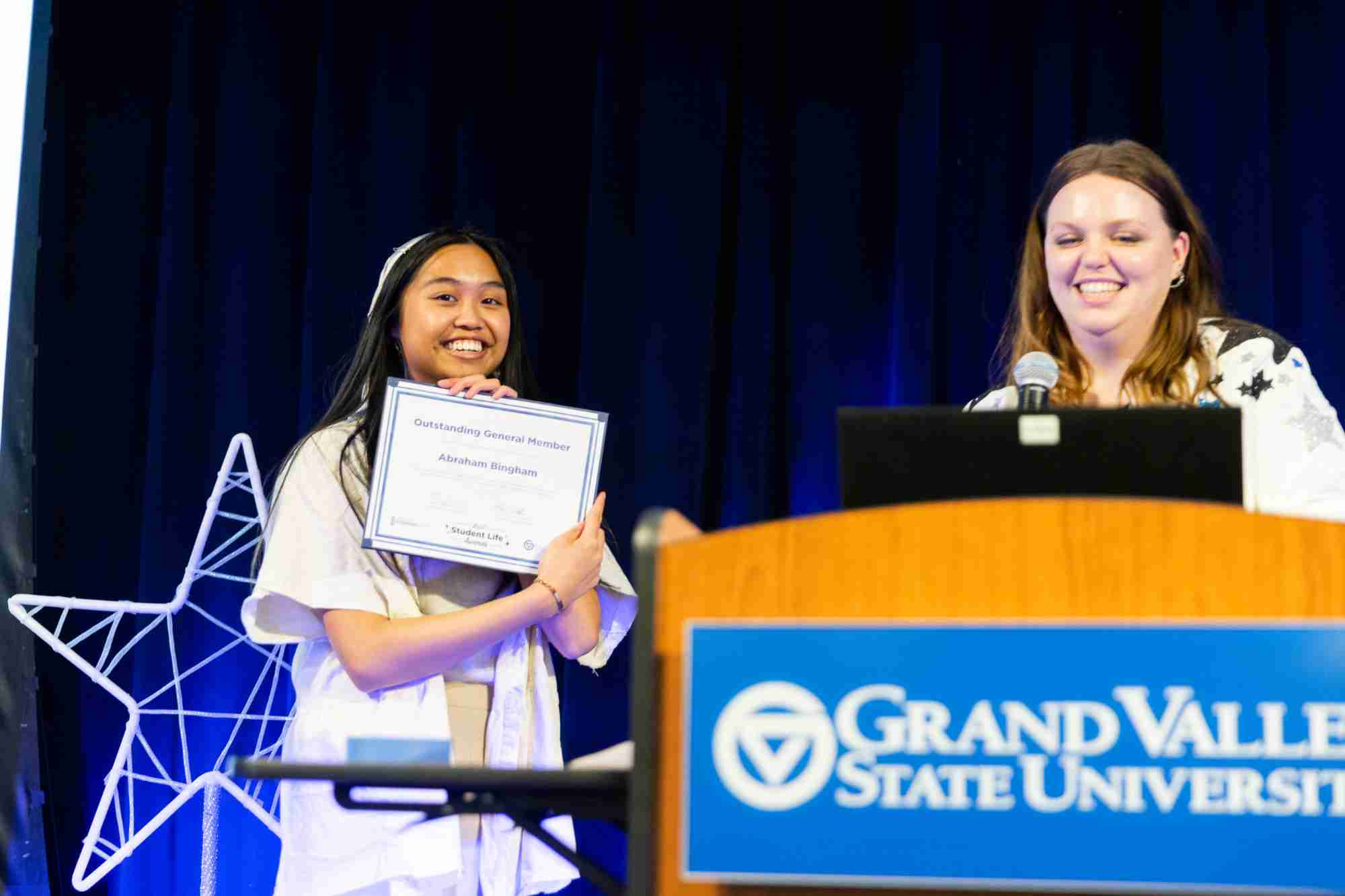 A student receiving a I Am Grand Valley Award on stage