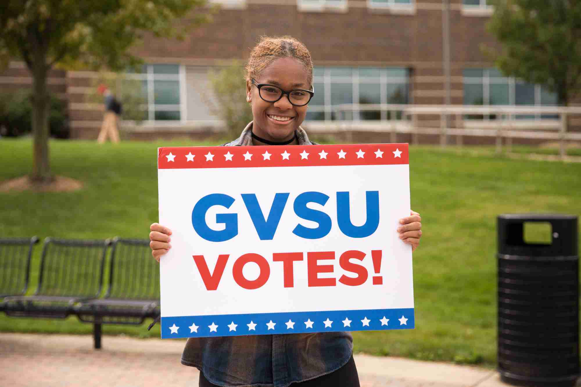 A student holding up a GVSU Votes sign 