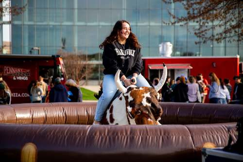A girl riding a mechanical bull and having fun at ExtravaGRANDza